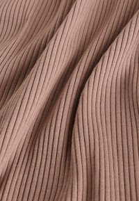 Rebrasta tkanina u mekom mauve tonu, s vertikalnim linijama i glatkom teksturom, prikazuje nabore i prirodno padaње.