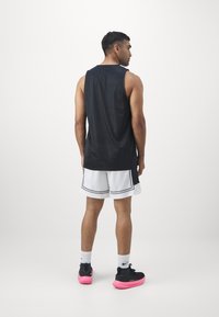 Black mesh tank top, white shorts with black and red accents, and black shoes with pink soles. Minimalist athletic design, breathable fabric.