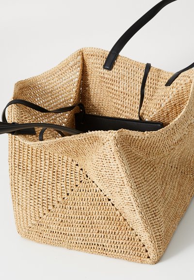 Borsa a rete con manici in pelle nera. Presenta una larga apertura superiore e un motivo testurizzato. Colore naturale con una forma geometrica e angolare.