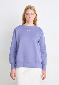 Sudadera púrpura hecha de una tela suave y transpirable, con un cuello redondo, mangas largas y un pequeño logo blanco de Nike en el pecho.