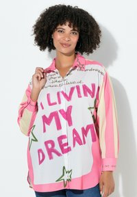 Kolorowa, oversized koszula z guzikiem w białym kolorze z różowymi i zielonymi akcentami. Posiada wzory z tekstem i gwiazdkami. Długie rękawy i kołnierzyk.