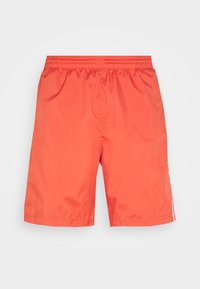 Pantaloni da bagno corallo con cintura elastica, realizzati in tessuto leggero. Presentano strisce laterali e una trama liscia e uniforme.