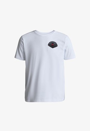 Biała koszulka z krótkim rękawem i okrągłym dekoltem z czarnym logo w kształcie tarczy z czerwonym dłonią i napisem "ZAVETT" na lewej piersi.