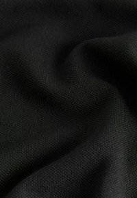 Tessuto nero con una leggera lucentezza, caratterizzato da un motivo intrecciato e una superficie liscia, che crea leggere ondulazioni e pieghe.