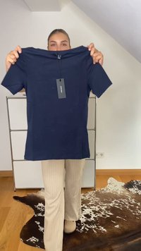 Tamsiai mėlyna trumpomis rankovėmis marškinėliai, pagaminti iš minkštos medžiagos, su tiesiu kirpimu ir prisegta etiketė, laikomi prieš neutralų foną.