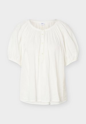 Blouse blanche à manches courtes avec manches bouffantes élastiquées, encolure ronde, patte de boutonnage devant et détails en tissu doux froncé.