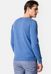 Niebieski sweter z dzianiny, z okrągłym dekoltem, długimi rękawami oraz ściągaczami przy rękawach i u dołu. Tkanina ma miękką strukturę.