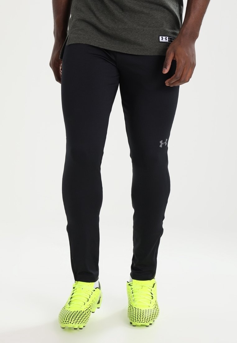 Černé sportovní legíny s obepnutým střihem a reflexními detaily loga. V kombinaci se světlými žlutými kopačkami s texturovaným vzorem.