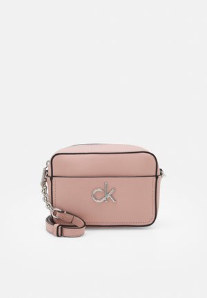 Kompakt blush pink læder crossbody taske med sort kant, sølv "ck" logo og justerbar rem med kædedetalje.