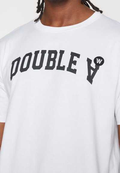 Baltas medvilninis marškinėliai su juodu kreivu "DOUBLE A" teksto grafiniais elementais ir apvaliu juodu ženkliuku su baltu logotipu ant krūtinės.