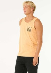 Pfirsichfarbenes Tanktop aus Baumwolle mit rundem Ausschnitt und einem Frontlogo einer Welle in einem Quadrat. Lässige und figurbetonte Silhouette.