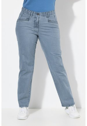 Vaqueros de denim azul claro con un corte relajado, que cuentan con una cintura elástica, bolsillos frontales y detalles de costura sutiles. Combinados con zapatillas blancas.