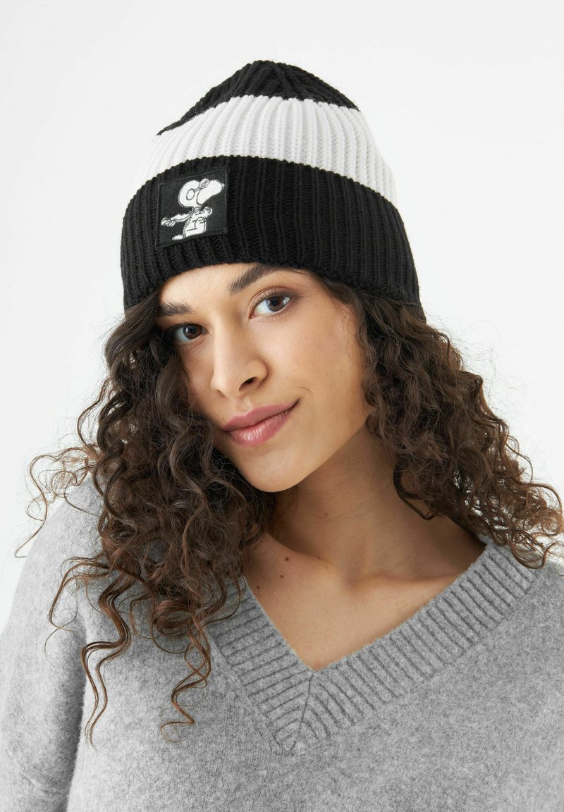 Zwart-wit gebreide beanie met een geribbelde textuur. Voorzien van een Snoopy-applicatie op de voorkant. Tapered kroon en een strakke pasvorm.