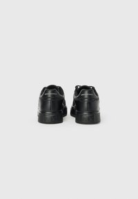 Adidași negri cu un superior din piele netedă, talpă din cauciuc texturat și logo-ul „AX” embosat pe călcâi. Design cu șireturi și guler căptușit.