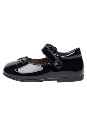 Schwarzer Mary Jane Schuh aus Lackleder mit Klettverschluss und einer kleinen Schleife auf der abgerundeten Schuhspitze, für Kinder entworfen.