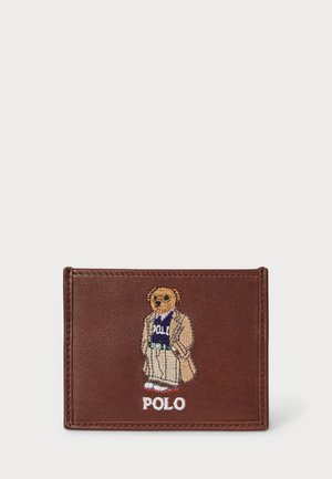 Barna bőr pénztárca, hímzett medvével, aki öltönyt visel, a design alatt "POLO" felirattal. Simogató tapintású, tiszta varrással.