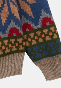 Manches de pull en tricot avec des motifs géométriques en bleu, rouge, vert, pêche et orange, avec des poignets côtelés beige.