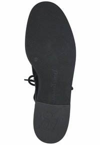 Zapato negro con cordones y suela de goma texturizada. Presenta una parte superior suave y un logo grabado en la suela, diseñado para comodidad y estabilidad.