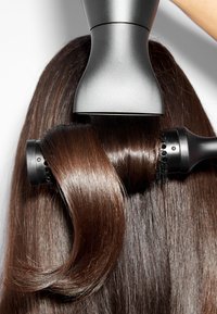 Des cheveux longs et bruns coiffés avec une brosse ronde et un sèche-cheveux pour une finition lisse et brillante.