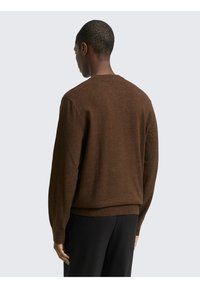 Brauner gestrickter Pullover mit Rundhalsausschnitt, gerippten Bündchen und Saum. Der Stoff hat eine subtile Textur und eine lockere Passform für zusätzlichen Komfort.