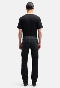 Czarna bawełniana koszulka z okrągłym dekoltem w zestawie z ciemnymi dżinsami. Dżinsy mają prosty krój i cztery kieszenie.