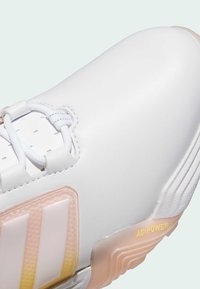 Fehér tornacipő texturált szintetikus felsőrésszel, kontrasztos rózsaszín és fehér három csíkkal, valamint aranyszínű "ADIPOWER" logóval a talpon.