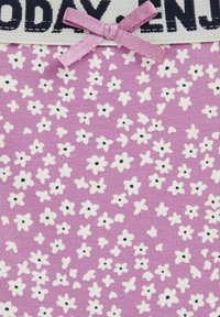 Ljusrosa tyg med en texturerad yta, med vita och svarta blommönster samt en övre rad med "IDAG" i mörka bokstäver och en rosa rosett som accent.