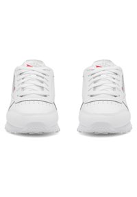 Baltos sportinės batelės su lygiu odos paviršiumi, suvarstymo sistema ir skylelėmis ant pirštų srities. Subtilūs pilki ir raudoni akcentai.