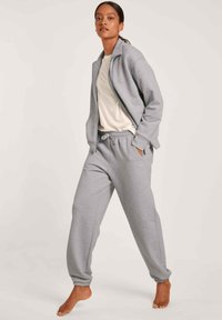 Grijze zip-up sweatshirt en bijpassende sweatpants gemaakt van zachte stof, met een ontspannen pasvorm, zakken en elastische manchetten.