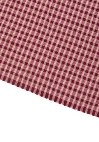 Röd och ljusbeige rutigt tyg med ett rutmönster, mjuk textur och fransad kant. Designen har enhetliga rutnätsliknande former.