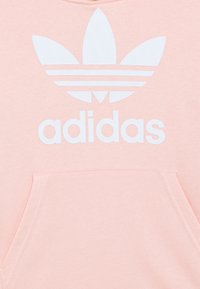 Rosa sweatshirt med en jämn textur, med en stor vit Adidas-logotyp och trefoil-design på framsidan, samt en känguruficka.