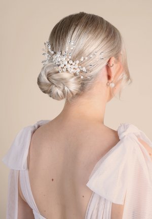 Accessorio per capelli con ciuffi di perle off-white e dettagli in argento su una delicata base di filo, modellato all'interno di un chignon basso. Spalline morbide e trasparenti.