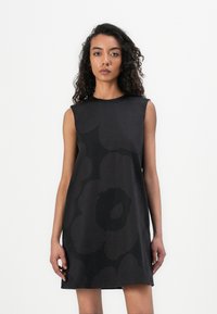 Sleeveless black dress with a floral pattern, featuring varying shades and textures. Simple, A-line design with a round neckline.