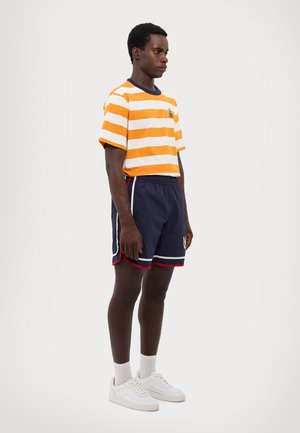 Orange and white striped short-sleeve shirt, navy shorts with red trim, white sneakers, and matchings socks. Casual sportswear design.