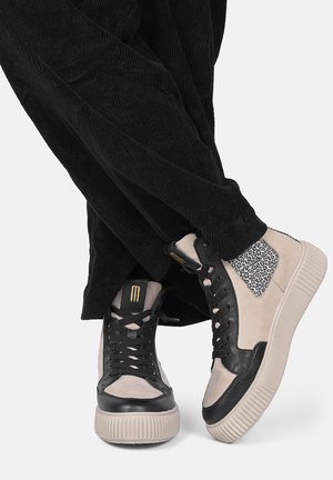 Le scarpe da ginnastica alte presentano una combinazione di pelle nera e suede beige, con un accento a stampa leopardata e dettagli in oro sul linguetta.
