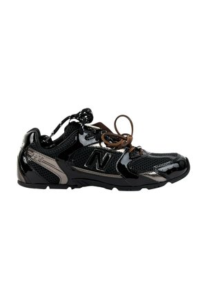 Baskets basses New Balance noires et grises avec mesh et cuir verni brillant, avec des lacets noirs et marron.