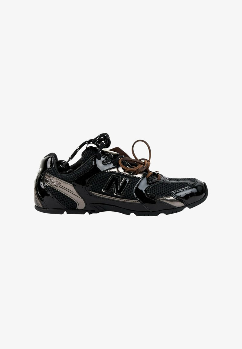 Baskets basses New Balance noires et grises avec mesh et cuir verni brillant, avec des lacets noirs et marron.