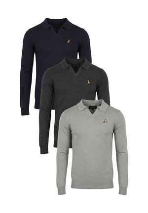 Man in lichtgrijs poloshirt met lange mouwen en klein logo, zwarte broek en zwarte sneakers, staand en de kraag aanrakend op een witte achtergrond.