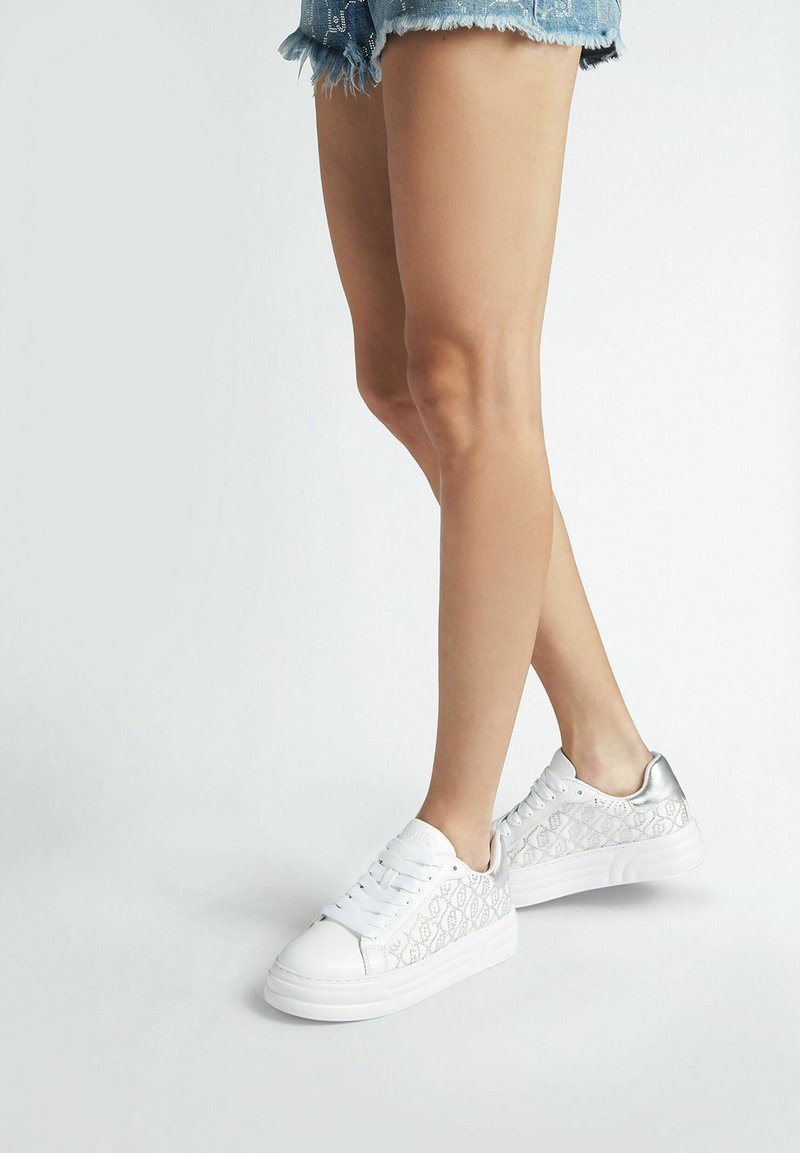 Sneaker bianchi con un motivo argentato testurizzato sui lati, caratterizzati da una punta liscia e una cavigliera imbottita. Suola in gomma bianca.