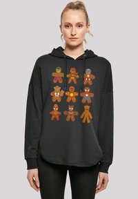 Felpa nera con cappuccio decorata con colorati disegni di biscotti di pan di zenzero che ricordano supereroi. Il cappuccio ha i lacci; il tessuto sembra morbido e strutturato.