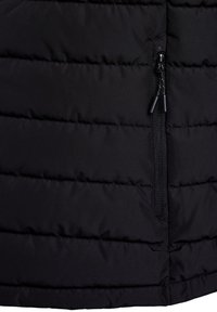 Svart pufferjacka med horisontella quiltade paneler, en sidofick med dragkedja och en slät, matt tygtextur.