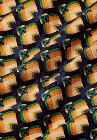Tessuto con motivo caratterizzato da un design geometrico con rettangoli multicolori in arancione, beige, verde e blu su uno sfondo nero.
