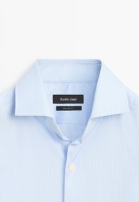 Lichtblauw gestreept shirt met een klassieke kraag, knoopsluiting en een gladde textuur. Label met de tekst "Massimo Dutti", met wasinstructies eronder.