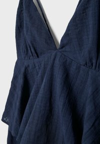 Navy blue textured sleeveless dress with deep V-neckline and gathered waist detail on lightweight fabric.