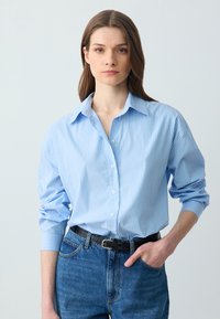 Lichtblauw gestreept overhemd met knopen, een gespreide kraag, lange mouwen en een relaxed fit, gecombineerd met high-waisted denim jeans.