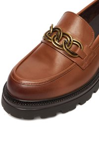 Rudi odiniai bateliai be kulno su dideliu auksiniu grandinės akcentu, minkštu padu ir tekstūruotu juodu guminiu padu. Lygus paviršius su siūlių detalėmis.