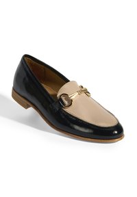 Zwarte en beige gepatineerde leren instapper met een gouden accent, ronde neus en lage houten hak, met een decoratieve kettingdetail.