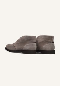 Chukka boots in zacht grijs suede, met een ronde neus, eenvoudig vetersluiting ontwerp en een lage zwarte hak voor een klassieke silhoutte.