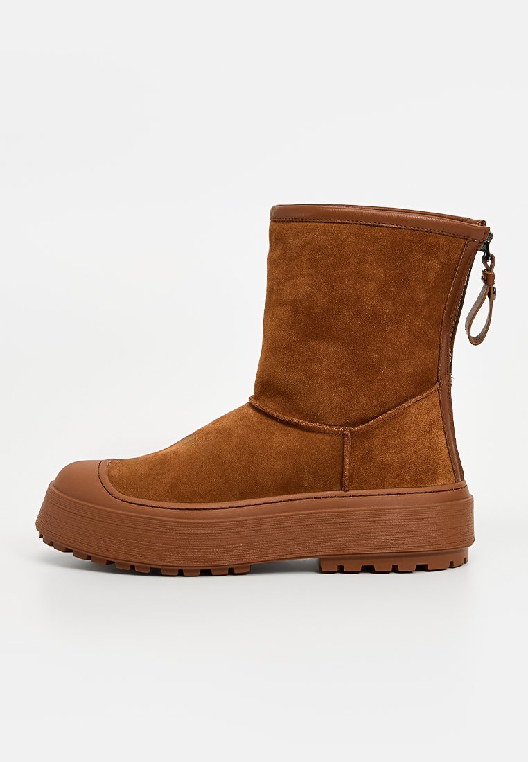 Braune Wildleder-Ankle Boots mit strukturiertem Finish, einer Gummisohle und einem seitlichen Reißverschluss für einfaches An- und Ausziehen. Verfügt über eine leichte Plateausohle für zusätzlichen Komfort.