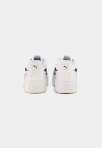 Sneakers bianchi con tomaia in pelle liscia, collare imbottito e dettagli neri. Presentano una suola bianca spessa e il logo Puma sul tallone.